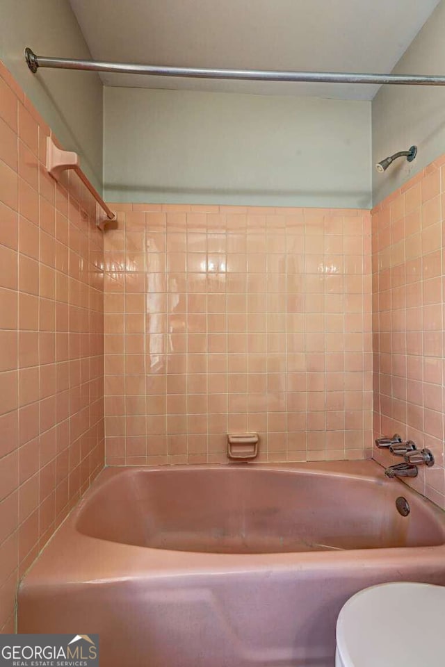 bathroom with tiled shower / bath combo and toilet