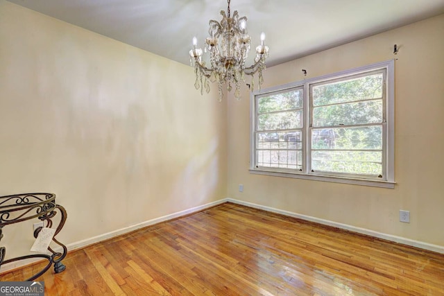 unfurnished room with a chandelier, light hardwood / wood-style floors, and a wealth of natural light