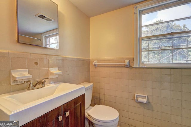 bathroom featuring a wealth of natural light, tile walls, and toilet