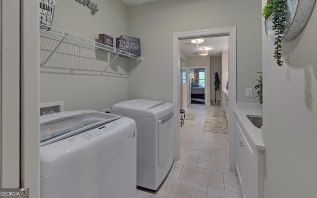 clothes washing area featuring washer and clothes dryer, light tile patterned floors, and sink