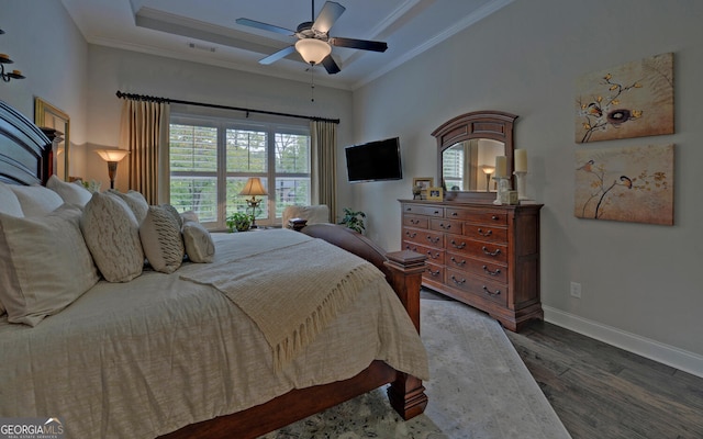 bedroom featuring dark hardwood / wood-style floors, a raised ceiling, ceiling fan, and ornamental molding