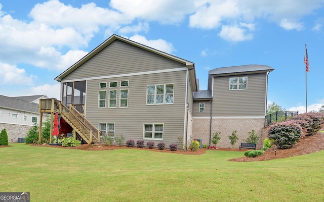 rear view of property featuring a sunroom, a yard, and central AC unit