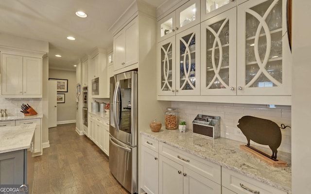 kitchen with white cabinetry, tasteful backsplash, light stone counters, dark hardwood / wood-style flooring, and stainless steel fridge