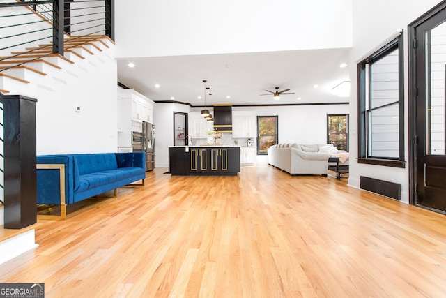 living room with ceiling fan, light hardwood / wood-style flooring, sink, and ornamental molding