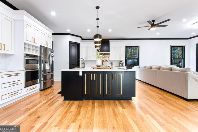 kitchen featuring stainless steel appliances, pendant lighting, a center island with sink, white cabinets, and light hardwood / wood-style floors