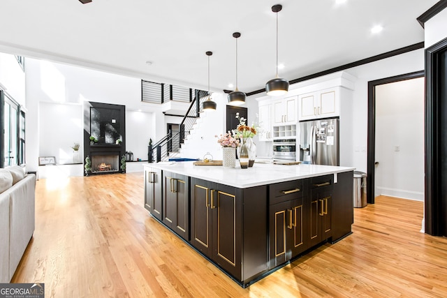 kitchen featuring hanging light fixtures, a center island, stainless steel appliances, and light hardwood / wood-style floors