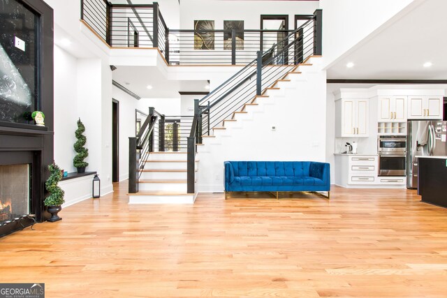 entryway featuring a high ceiling, light wood-type flooring, and crown molding