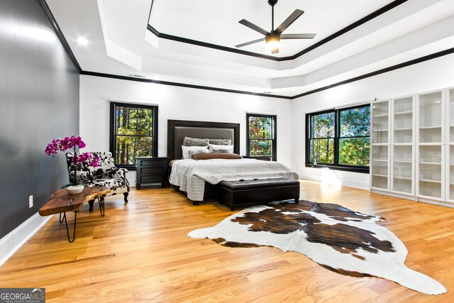 bedroom with a tray ceiling, ceiling fan, hardwood / wood-style floors, and crown molding