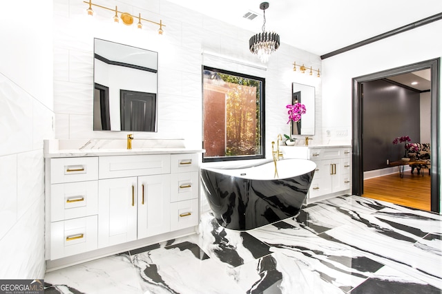 bathroom with vanity, an inviting chandelier, a tub, and tile walls