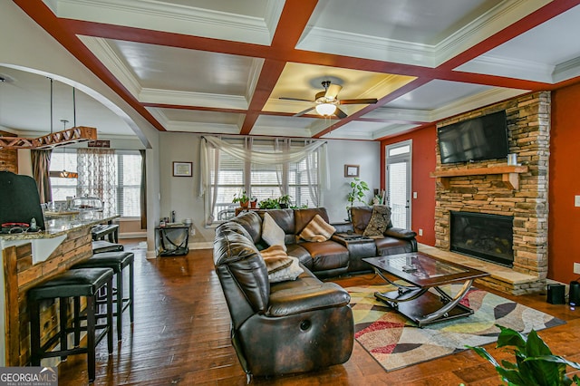 living room featuring coffered ceiling, dark hardwood / wood-style floors, ceiling fan, ornamental molding, and a fireplace