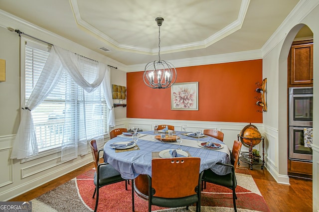 dining room featuring a notable chandelier, dark hardwood / wood-style flooring, ornamental molding, and a tray ceiling