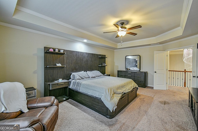 bedroom with ceiling fan, ornamental molding, light carpet, and a tray ceiling