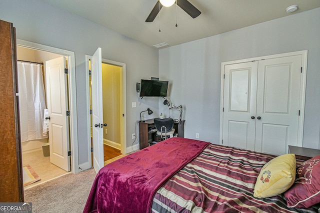 bedroom featuring ceiling fan, ensuite bathroom, light carpet, and a closet