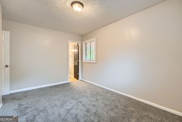 carpeted empty room featuring a textured ceiling