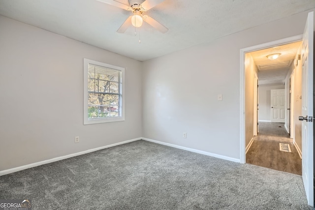 unfurnished room featuring a textured ceiling, dark carpet, and ceiling fan