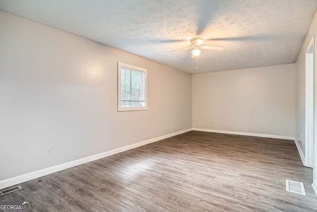 empty room with a textured ceiling, dark hardwood / wood-style flooring, and ceiling fan