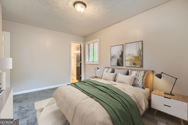 carpeted bedroom with ensuite bathroom and a textured ceiling