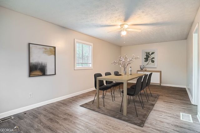 dining room with hardwood / wood-style floors, ceiling fan, and a textured ceiling