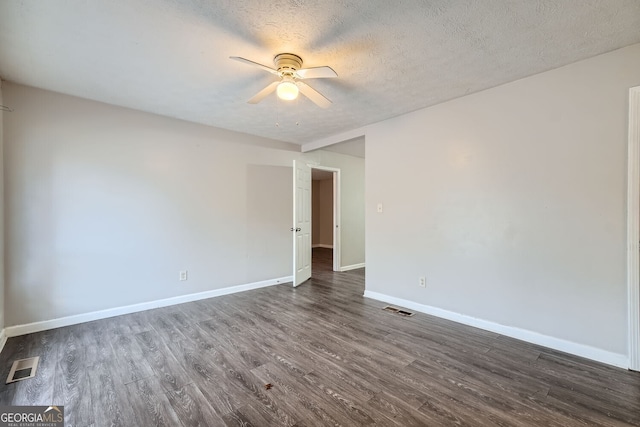 empty room with ceiling fan, dark wood-type flooring, and a textured ceiling