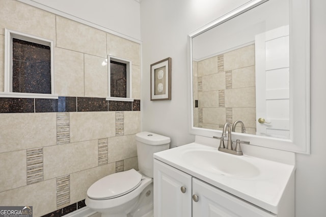 bathroom with vanity, toilet, and tile walls