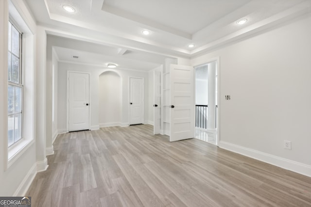 empty room featuring a raised ceiling and light hardwood / wood-style floors