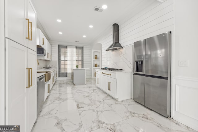 kitchen featuring white cabinets, wall chimney exhaust hood, stainless steel appliances, and tasteful backsplash