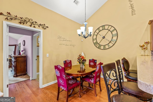 dining area featuring a notable chandelier, light hardwood / wood-style floors, and lofted ceiling