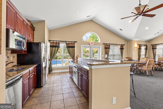 kitchen with sink, a breakfast bar area, ceiling fan, light tile patterned floors, and stainless steel appliances