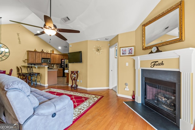 living room with light hardwood / wood-style floors, ceiling fan, and lofted ceiling