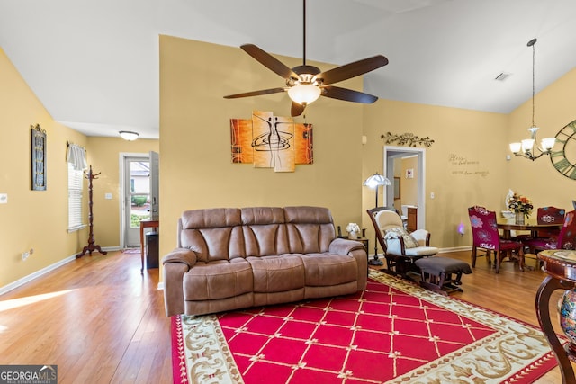 living room with hardwood / wood-style flooring, ceiling fan with notable chandelier, and lofted ceiling