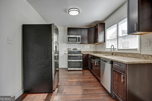 kitchen with dark brown cabinetry, sink, dark wood-type flooring, stainless steel appliances, and decorative backsplash