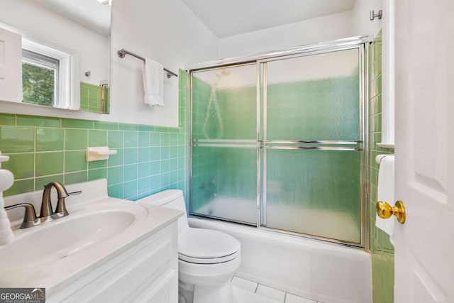 full bathroom featuring combined bath / shower with glass door, vanity, tile walls, tile patterned flooring, and toilet