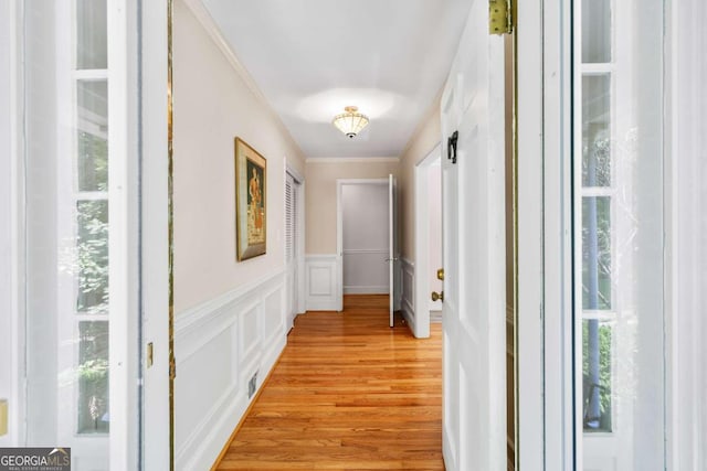 hallway featuring light wood-type flooring and ornamental molding