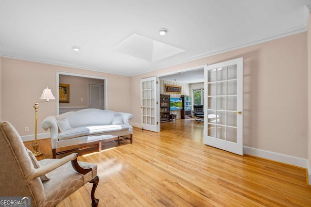 sitting room with light wood-type flooring, ornamental molding, and french doors