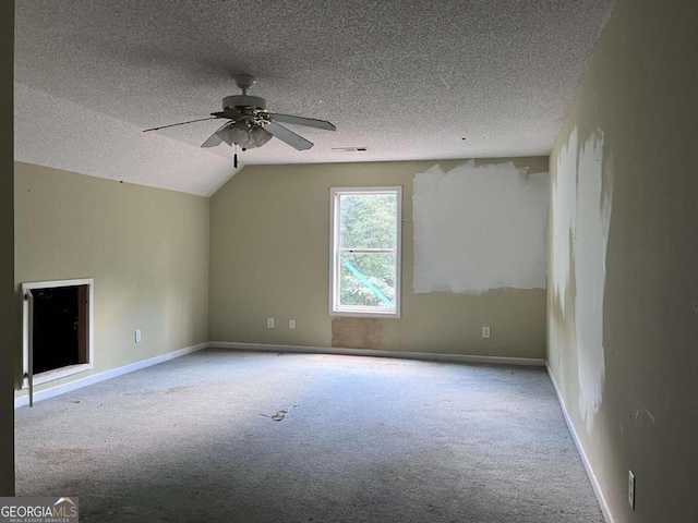 carpeted spare room featuring a textured ceiling, ceiling fan, and lofted ceiling