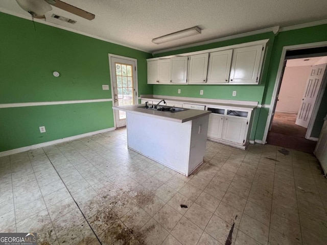 kitchen featuring white cabinetry, sink, a kitchen island with sink, and a textured ceiling