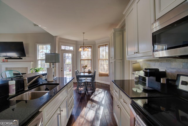 kitchen featuring dark hardwood / wood-style flooring, sink, electric range, decorative light fixtures, and dark stone countertops