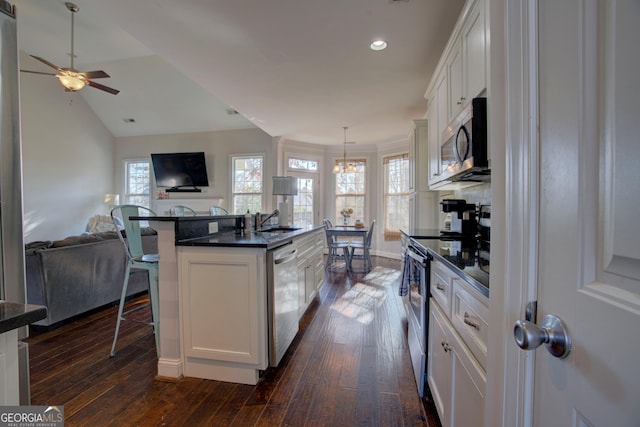 kitchen featuring a breakfast bar, stainless steel appliances, a kitchen island with sink, white cabinets, and dark hardwood / wood-style floors