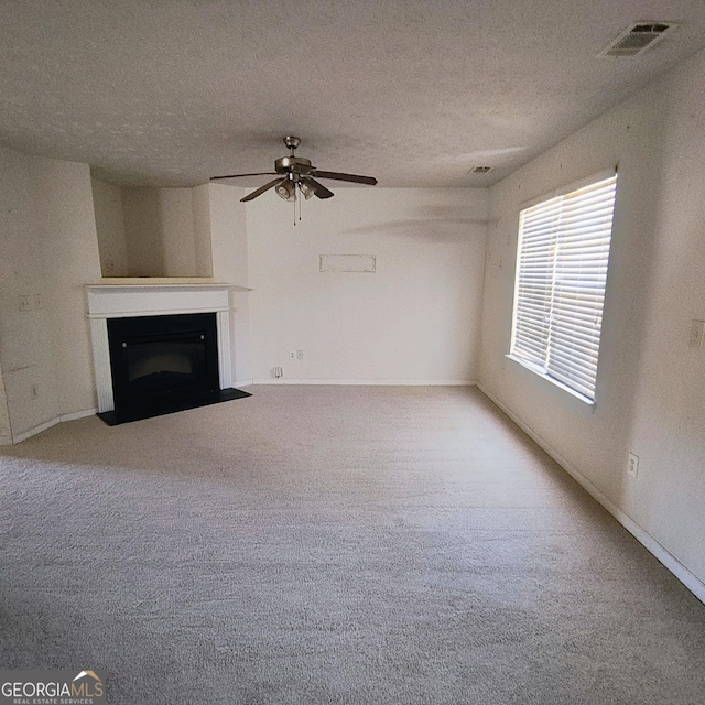 unfurnished living room featuring carpet, ceiling fan, and a textured ceiling