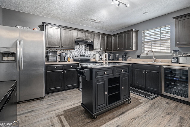 kitchen featuring wine cooler, a kitchen island, a textured ceiling, light hardwood / wood-style floors, and stainless steel appliances