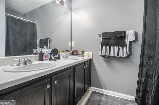 bathroom with tile patterned floors, vanity, and a textured ceiling