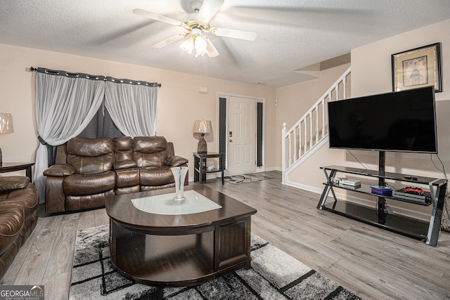 living room featuring hardwood / wood-style flooring, ceiling fan, and a textured ceiling