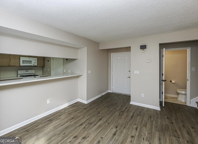 kitchen with kitchen peninsula, dark hardwood / wood-style flooring, white appliances, and a textured ceiling