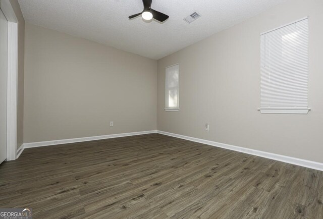 empty room featuring ceiling fan, dark hardwood / wood-style flooring, and a textured ceiling