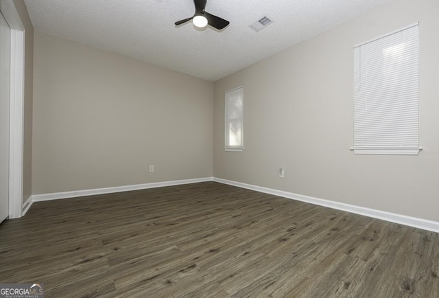 unfurnished room with dark wood-style floors, visible vents, ceiling fan, a textured ceiling, and baseboards