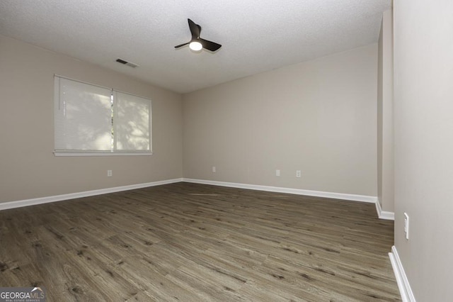 empty room with dark hardwood / wood-style floors and a textured ceiling