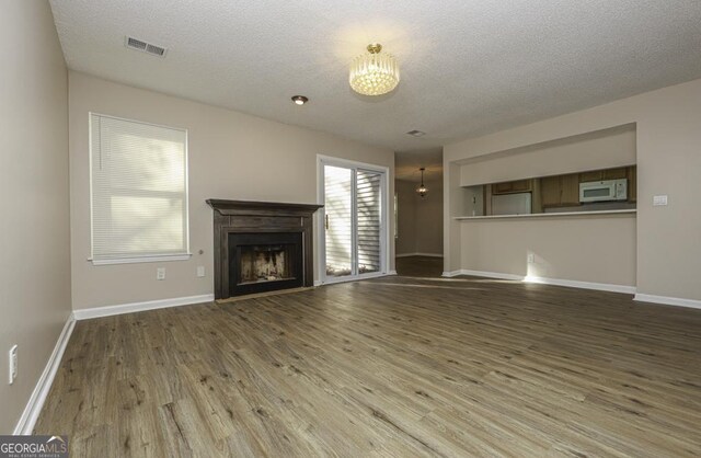 unfurnished living room featuring wood-type flooring, a textured ceiling, and a wealth of natural light