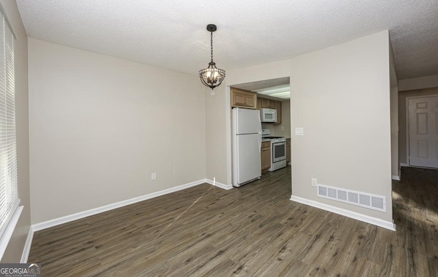 unfurnished dining area featuring baseboards, dark wood finished floors, visible vents, and an inviting chandelier