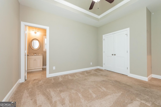 unfurnished bedroom with connected bathroom, crown molding, a raised ceiling, a closet, and light colored carpet