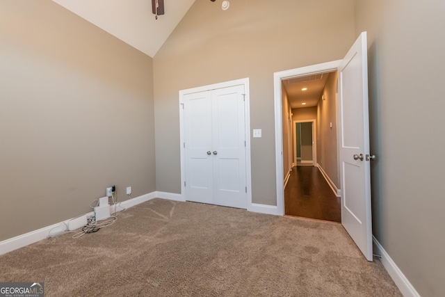 unfurnished bedroom featuring light colored carpet, high vaulted ceiling, and a closet